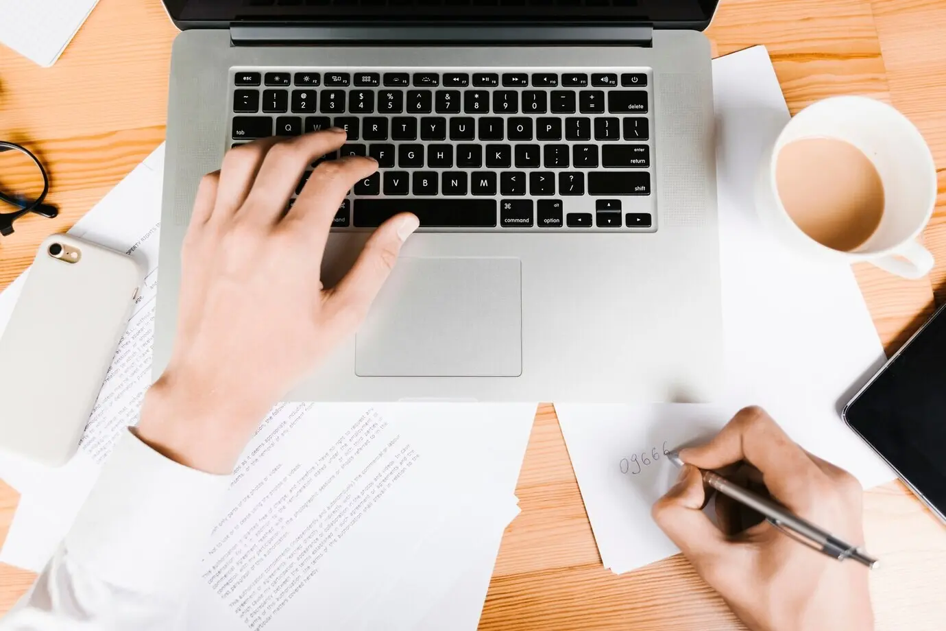 Draufsicht auf einen Arbeitsplatz mit Laptop und Kaffee.